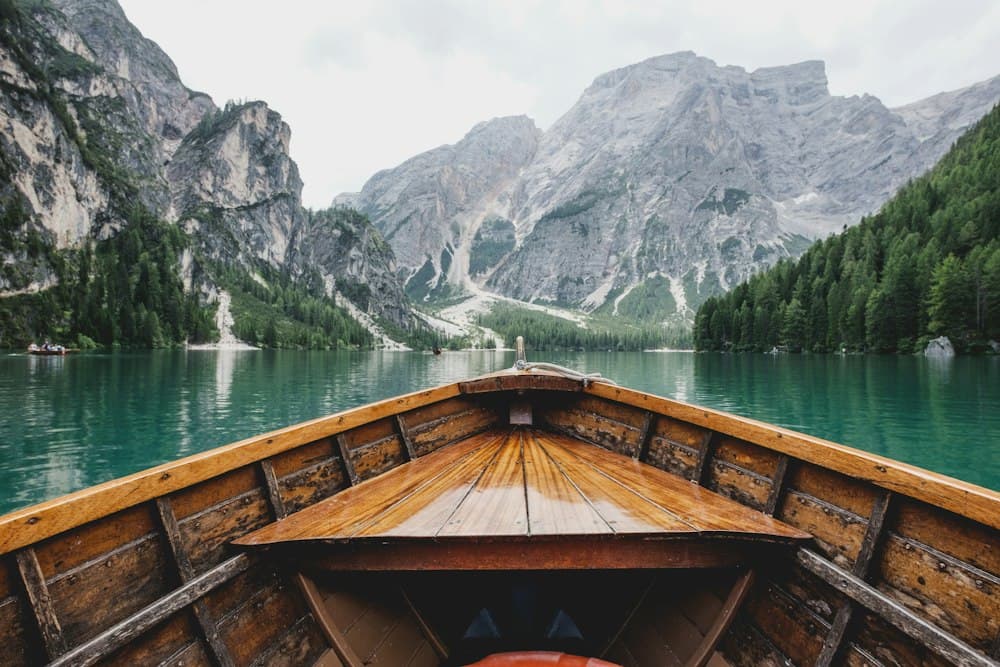 Wooden boat on a calm turquoise lake surrounded by mountains